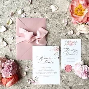 Zaproszenie ślubne Francuski Róż z delikatną wstążką i motywem akwarelowych róż w różowej kopercie.